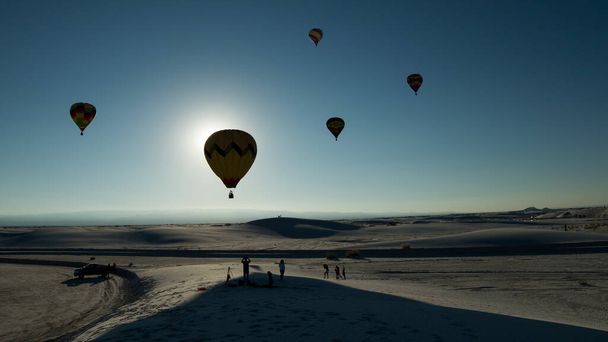 A breathtaking view of people watching the hot air balloons in a clear blue sky - Foto, Imagem