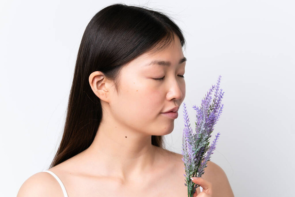 Young Chinese woman isolated on white background holding a lavender plant. Close up portrait - Photo, Image