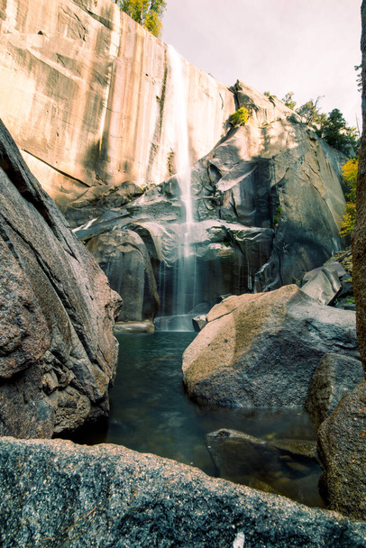 A vertical shot of waterfall and rocks in Yosemite Valley, USA - Fotó, kép