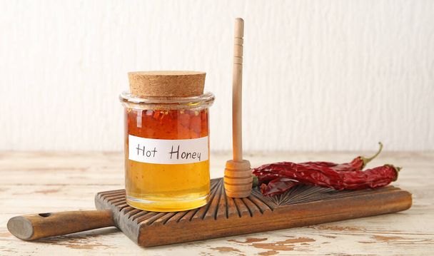 木のテーブルの上に熱い蜂蜜とドライチリペッパーのジャー - 写真・画像