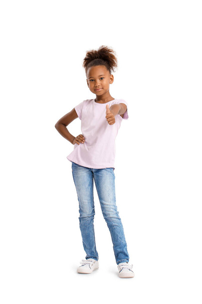 Petite fille afro-américaine en t-shirt montrant pouce sur fond blanc - Photo, image