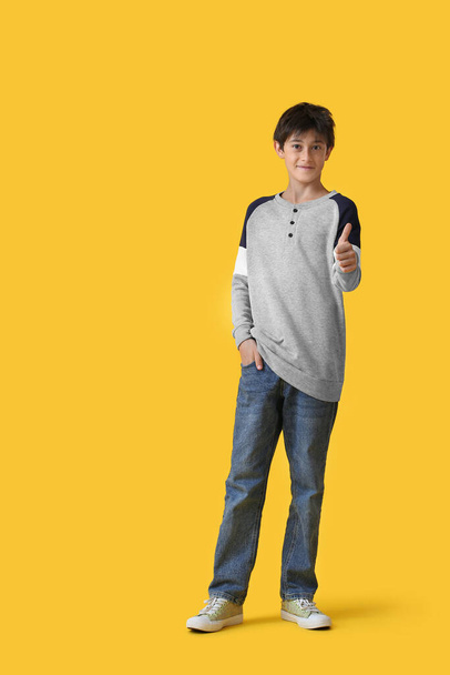 Teenage boy showing thumb-up on yellow background - Fotoğraf, Görsel