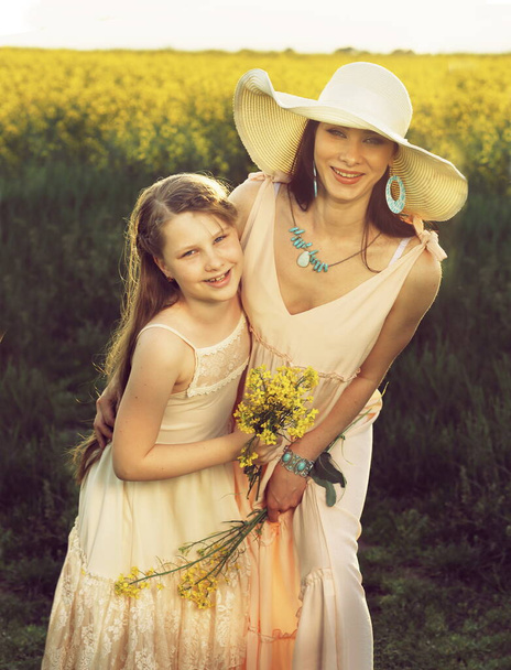 mother and daughter walking on the summer flower meadow - Fotoğraf, Görsel