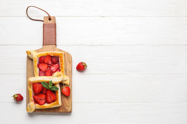 Brett mit Erdbeerblätterteig auf weißem Holzhintergrund - Foto, Bild