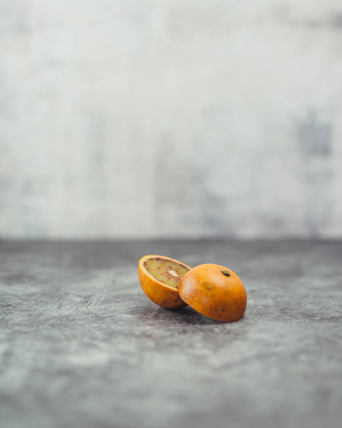 A vertical closeup of the sliced orange on the gray textured surface. - Valokuva, kuva