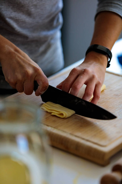 A vertical shot of a person cutting a dough with a knife in the kitc - Foto, imagen
