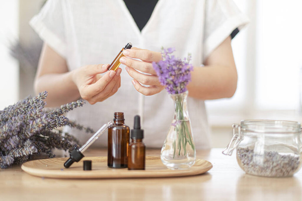 Utilisation d'huile essentielle naturelle dans un rituel de spa à domicile. Une femme prend soin de sa peau et de ses cheveux - Photo, image