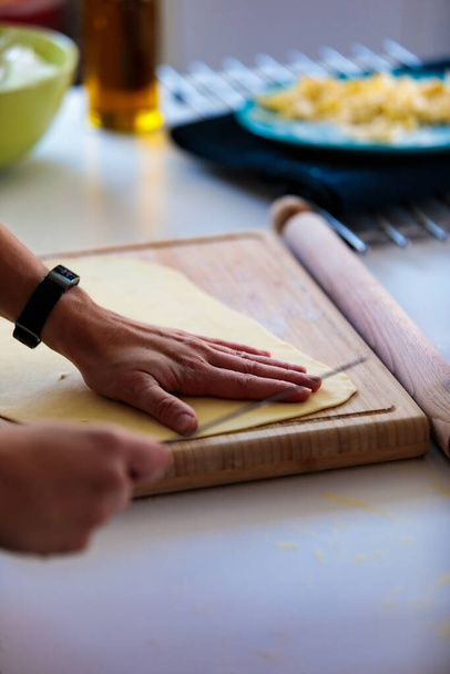 A vertical shot of a person ready to cut a dough with a knife in the kitchen - Foto, imagen
