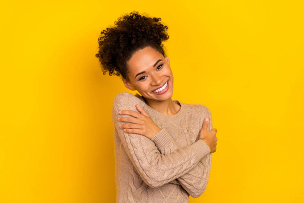 Photo of dreamy adorable woman wear beige sweater hugging herself isolated yellow color background. - Fotó, kép