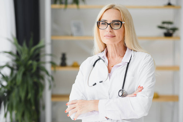 Successful mature caucasian senior female doctor in white coat at hospital - Valokuva, kuva