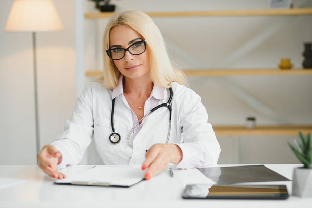 Mid age female doctor writing prescription. - Valokuva, kuva