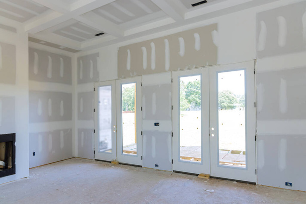 En préparation de la peinture d'une maison nouvellement construite, le mastic de finition est appliqué sur les murs d'un appartement vide - Photo, image