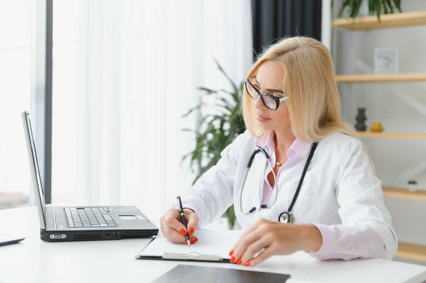 Mid age female doctor writing prescription. - Фото, зображення