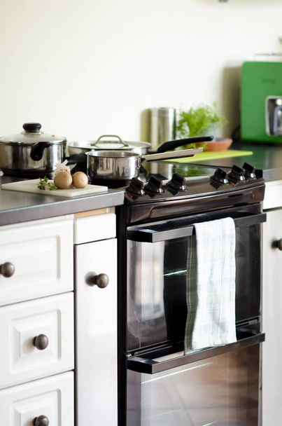 A kitchen with oven and various cooking utensils and pans - Foto, Imagen