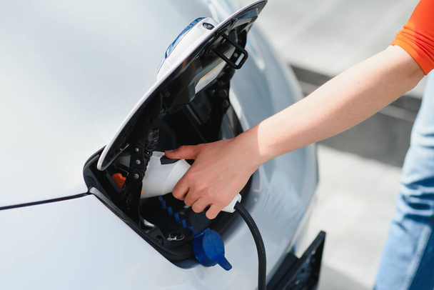 Woman is charging rental electric car. - Фото, зображення