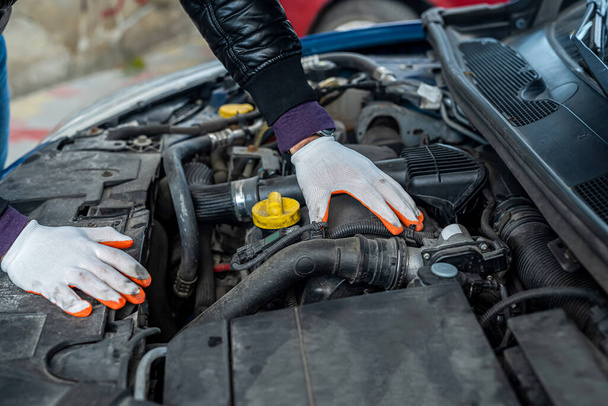 a professional good mechanic in special gloves diagnoses the car. The concept of car diagnostics - Photo, Image