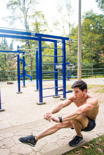 A young shirtless athletic man exercising in a park - Фото, зображення