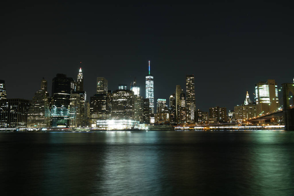 The mesmerizing scenery of the New York City Skyline at night from the bay with bright lights - Foto, imagen