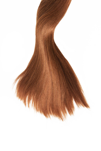 A strand of beautiful, soft and healthy brown and reddish hair isolated on a white background - Foto, imagen