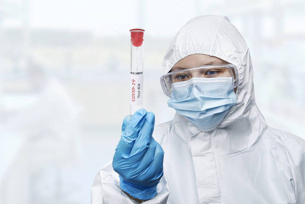 A medical worker in protective suit holding swab saliva sample for diagnostic coronavirus in lab - Foto, afbeelding