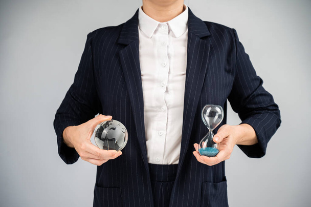 Business woman holding crystal globe and hourglass - Foto, imagen