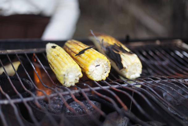 Een selectieve focus van gekookte maïs op een barbecue grill op een markt - Foto, afbeelding