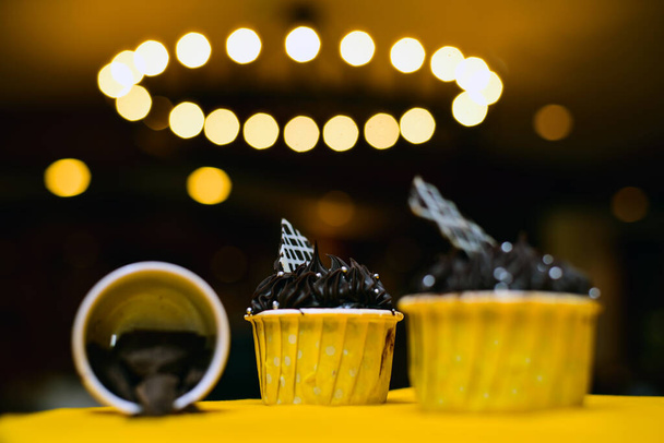 The dark chocolate cupcakes with frosted chocolate on the yellow background - Fotoğraf, Görsel