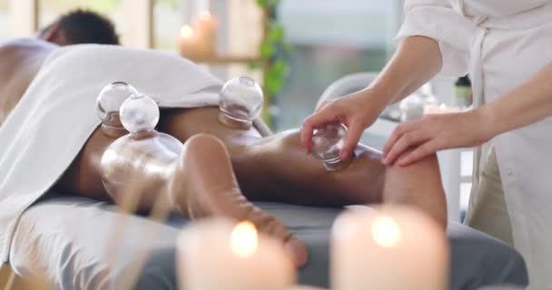 Man at spa getting cupping therapeutic leg massage treatment with vacuum cups. Closeup of beauty therapist treating body muscle pain with cupping therapy to remove toxins for healthy circulation. - Imágenes, Vídeo