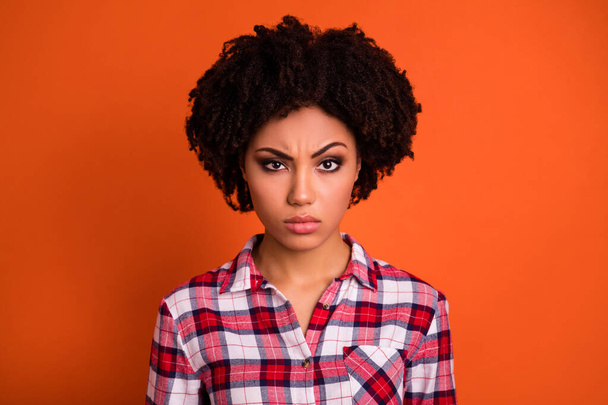 Photo of pretty doubtful lady dressed checkered shirt rising brow looking you isolated orange color background. - Foto, afbeelding