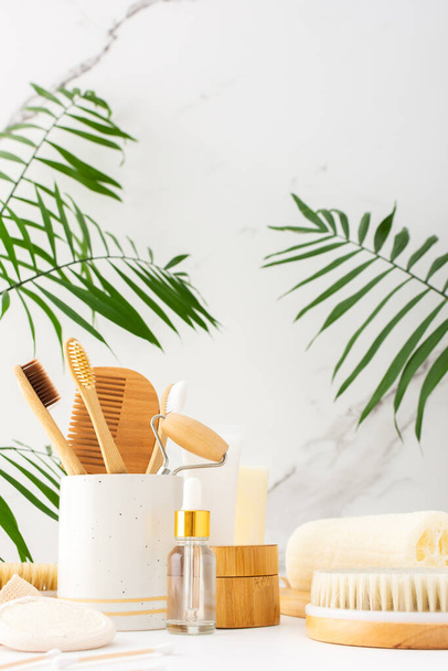 Wooden toothbrushes with natural bristles in a ceramic glass, face and skin care products, bottles with a pipette and a jar of cream, bath accessories, spa and beauty concept - Photo, Image