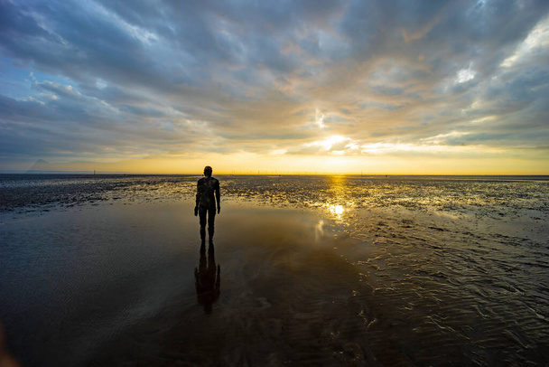 A beautiful shot of a sculpture at Another Place at Crosby Beach, UK at cloudy sunset - Foto, immagini