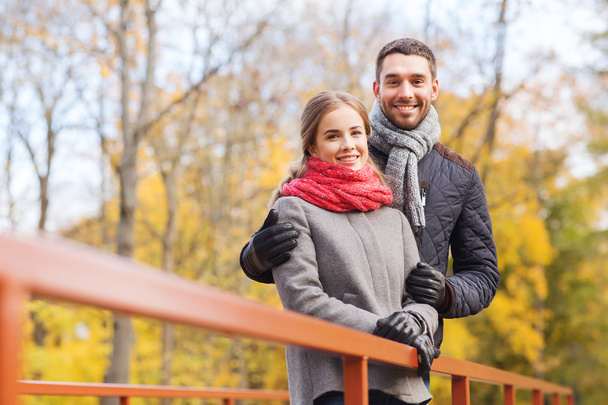 smiling couple hugging on bridge in autumn park - Foto, imagen