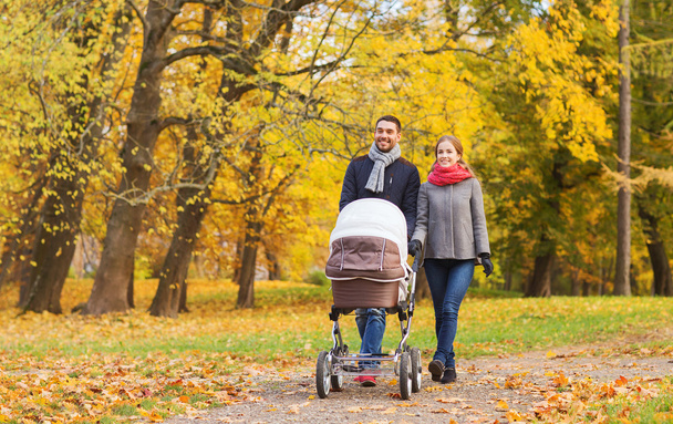 smiling couple with baby pram in autumn park - Zdjęcie, obraz