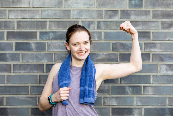 A young Caucasian woman shows his arm muscles during a fitness workout - Foto, imagen