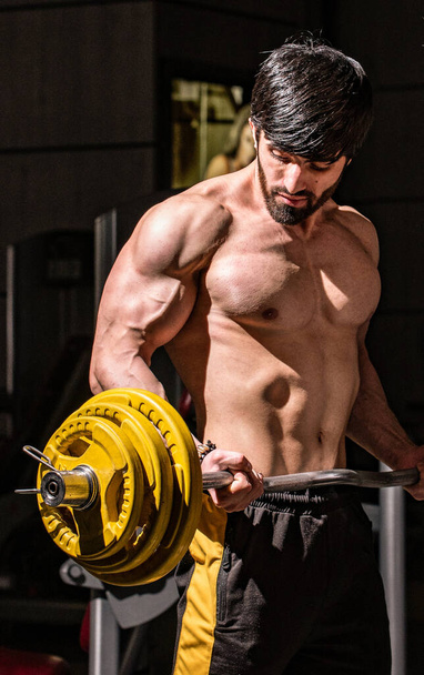 A vertical shot of a fit athletic muscular Caucasian man working out at the gym - Photo, Image