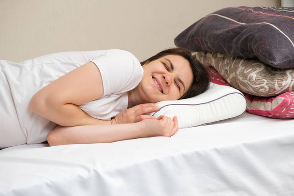 Nainen nukkuu ortopedinen tyyny valmistettu muisti vaahto, valitsemalla sen sijaan muita tyynyjä valmistettu fluff ja sintepon. - Valokuva, kuva