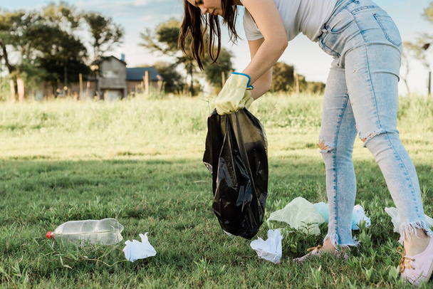 A young Hispanic girl collecting the garbage in a field in Argentina - Foto, Imagen