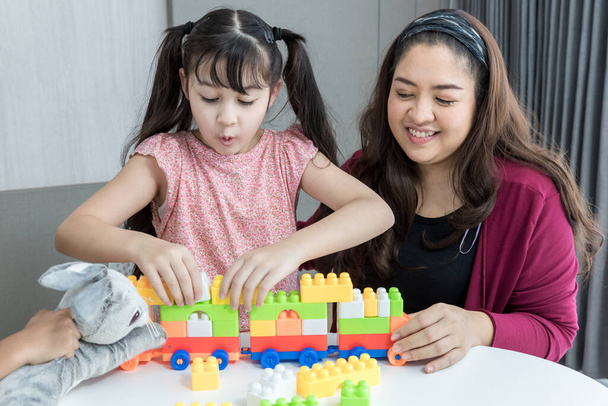 Mother and daughter at home playing the plastic block toys. Mom and and daughter are playing block toys - Foto, Imagen