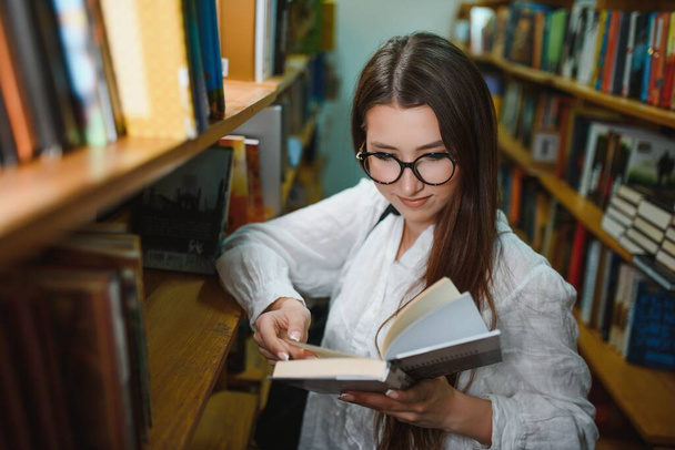 Portrait of a beautiful student in a library. - Foto, imagen