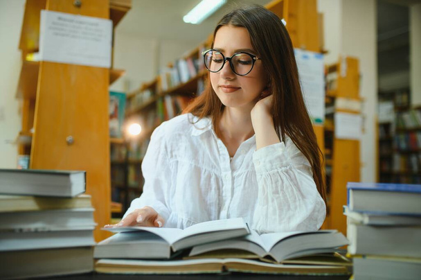 in the library - pretty female student with books working in a high school library - Foto, Bild