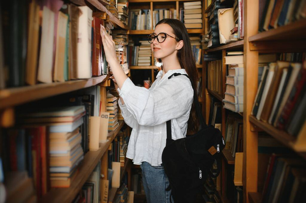in the library - pretty female student with books working in a high school library - Foto, Bild