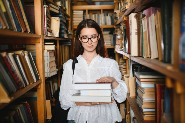 Portrait of a beautiful student in a library. - Zdjęcie, obraz