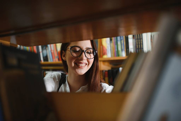 Portrait of a beautiful student in a library. - Valokuva, kuva