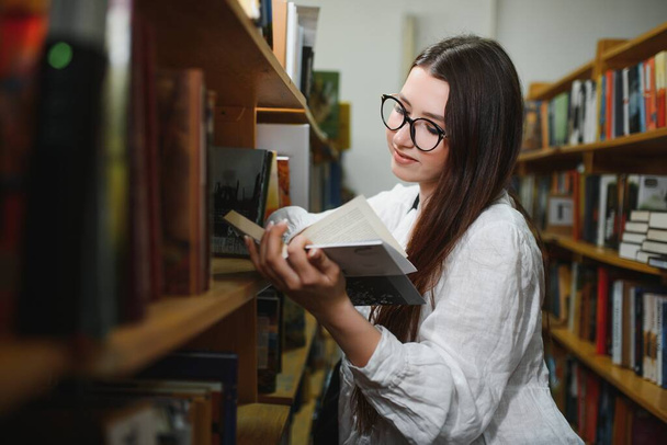 Beautiful girl in a library. - 写真・画像