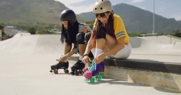 Full length of two friends getting ready for rollerskating in skate park. Cool young tying their laces together before having fun performing skating tricks outside. Happy diverse friends skating hobby - Footage, Video