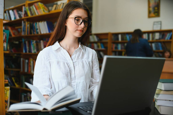 Portrait of a beautiful student in a library. - Foto, Imagen