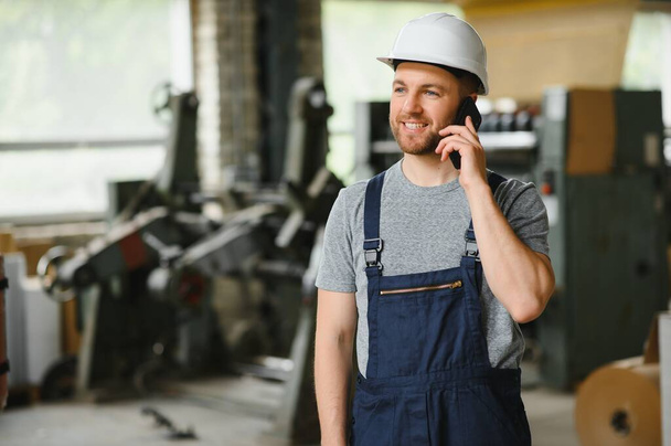 Management team, engineer, or foreman. Standing checking job information about industrial production management within the factory by phone. Teamwork concept. - Foto, Imagen