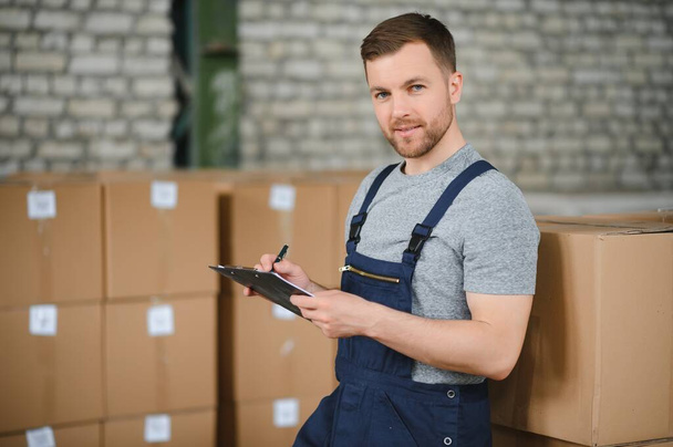 Warehouse worker carrying a carton for delivery to production stock - Photo, image