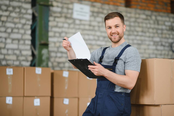 Warehouse worker carrying a carton for delivery to production stock - Photo, Image