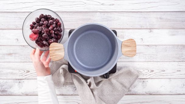 Step by step. Preparing mixed berry compote from frozen berries in a nonstick cooking pot. - Photo, Image